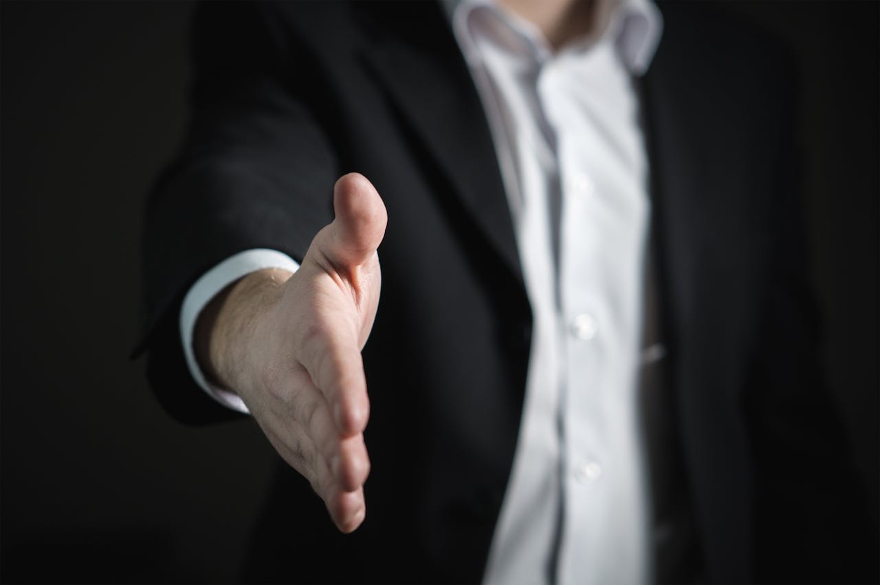 services-img-01 Close-up of a businessman extending hand for a handshake, symbolizing agreement and partnership.