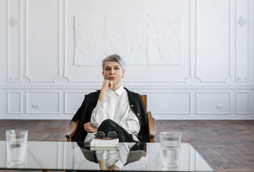 man-in-black-suit-sitting-on-brown-wooden-chair-4098254 Confident woman in a stylish office sitting at a glass table, symbolizing professionalism and focus.
